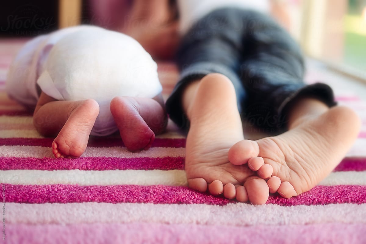Close up of a young child\'s feet lying next to his newborn sister\'s feet