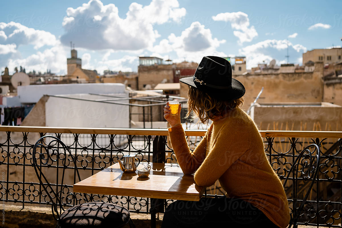A woman on a rooftop bar is drinking a tea