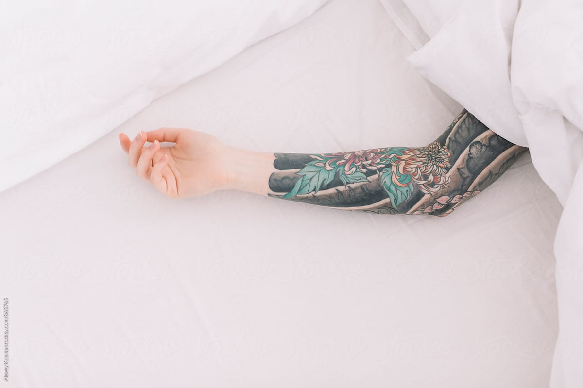 hand of young lady with tattoos in the bed.