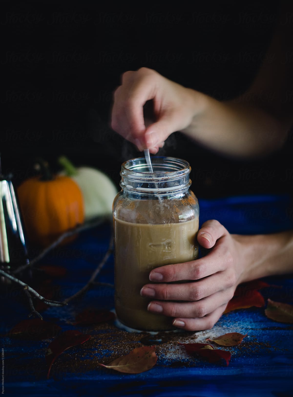 Female Stirring with Spoon a Mason Jar of Pumpkin Spice Coffee