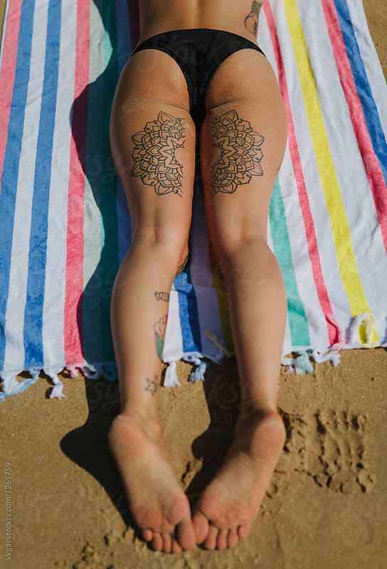 Tattooed legs and bum of a woman sunbathing