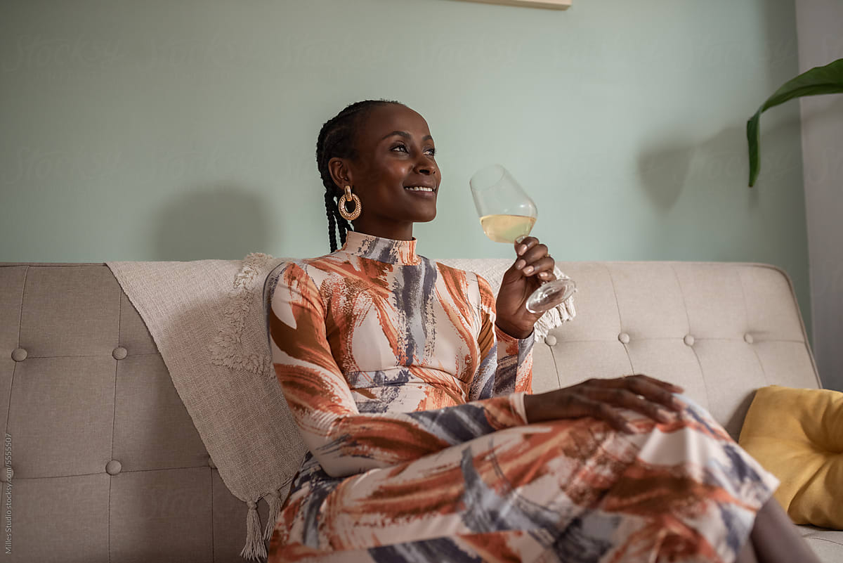 Smiling black woman drinking wine after work