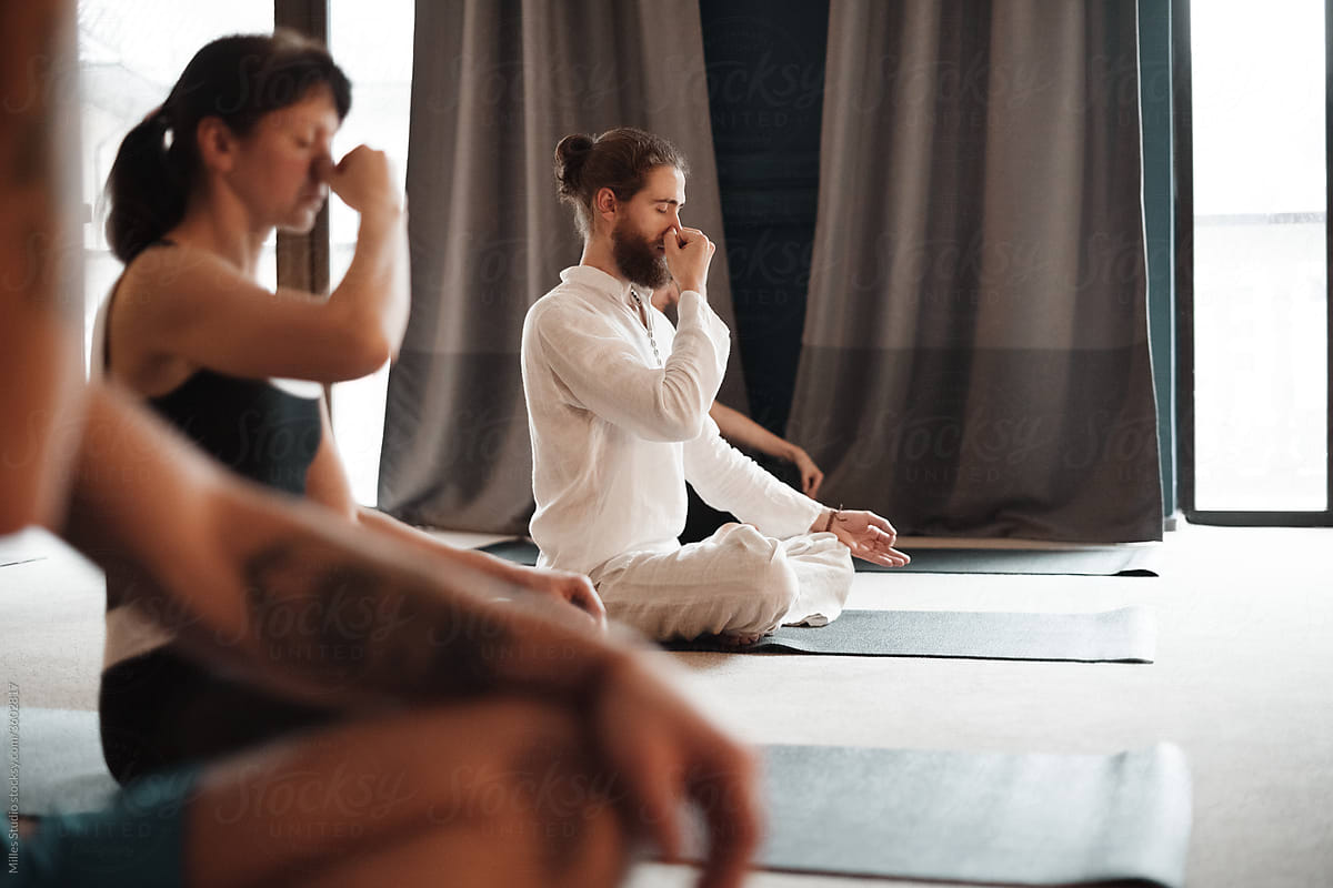 Man pinching nose and meditating with group