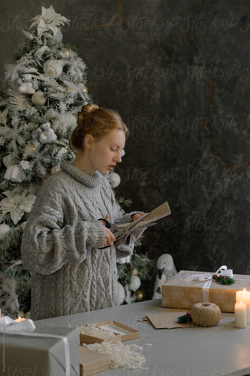 Portrait of a woman in a sweater at the table packing gifts