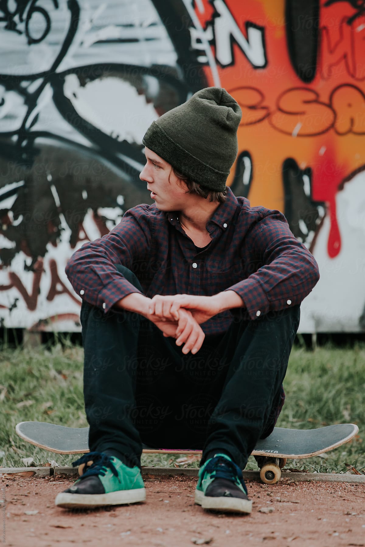 Young stylish man sitting on a skateboard