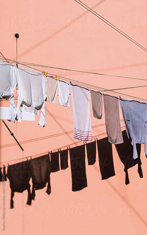 Washed clothes hanging out on line and drying on sun against pink facade.Venice/Italy