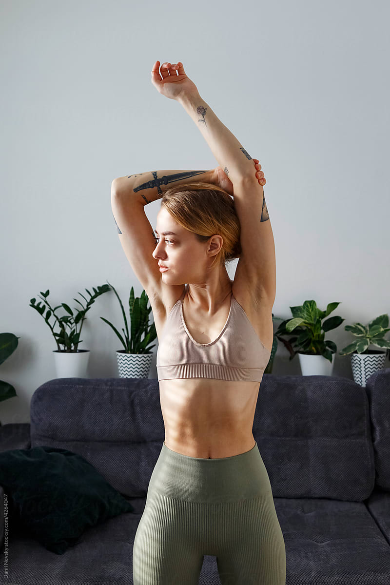 Graceful sportswoman stretching arms before training