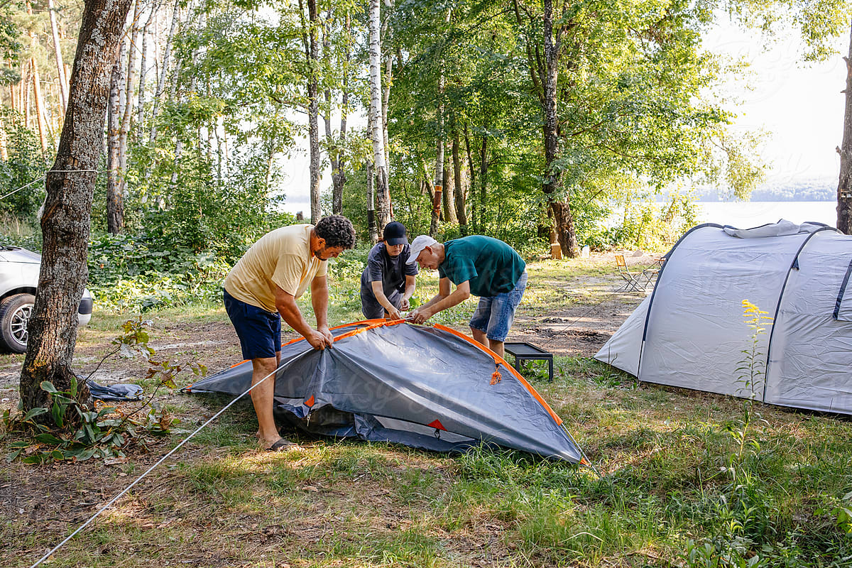 Friends Setting Up Tent by Lake at Daytime