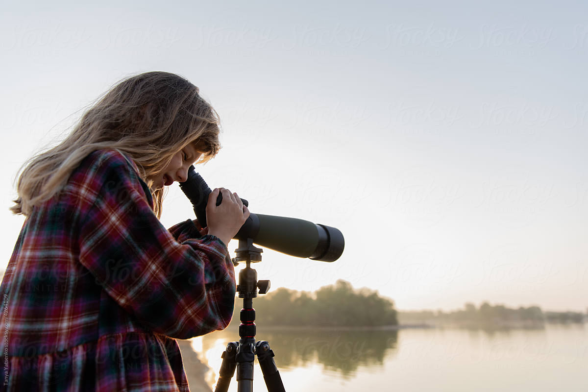 A girl looks at the birds through a telescope