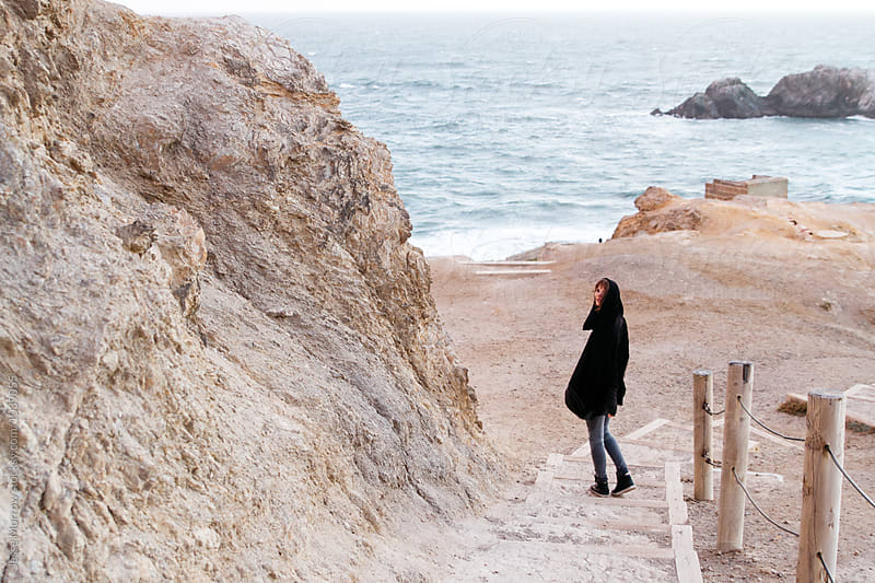 young woman walks down steps near ocean