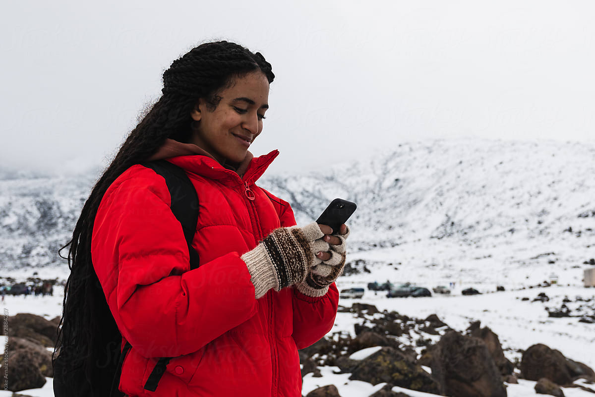 Girl smiling with mobile in a snowy volcano