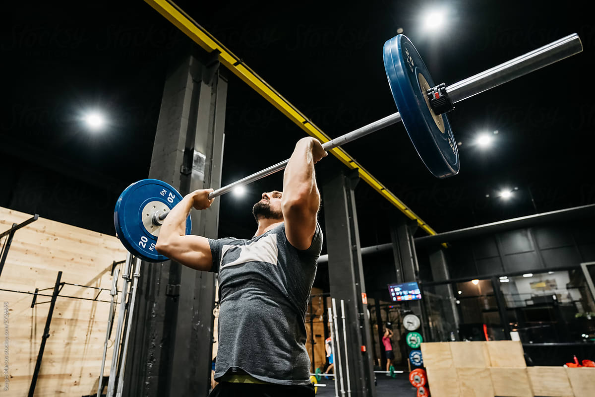 Athletic man doing a clean and jerk in a crossfit box