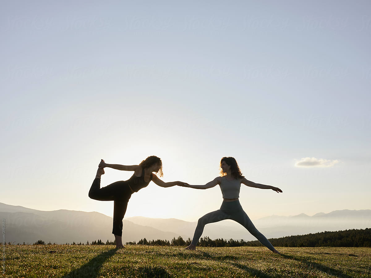 Women practicing yoga poses on lawn in morning light
