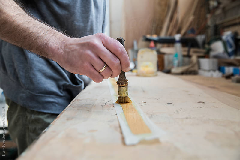 Closeup of a carpenter hand spreading glue on veneer