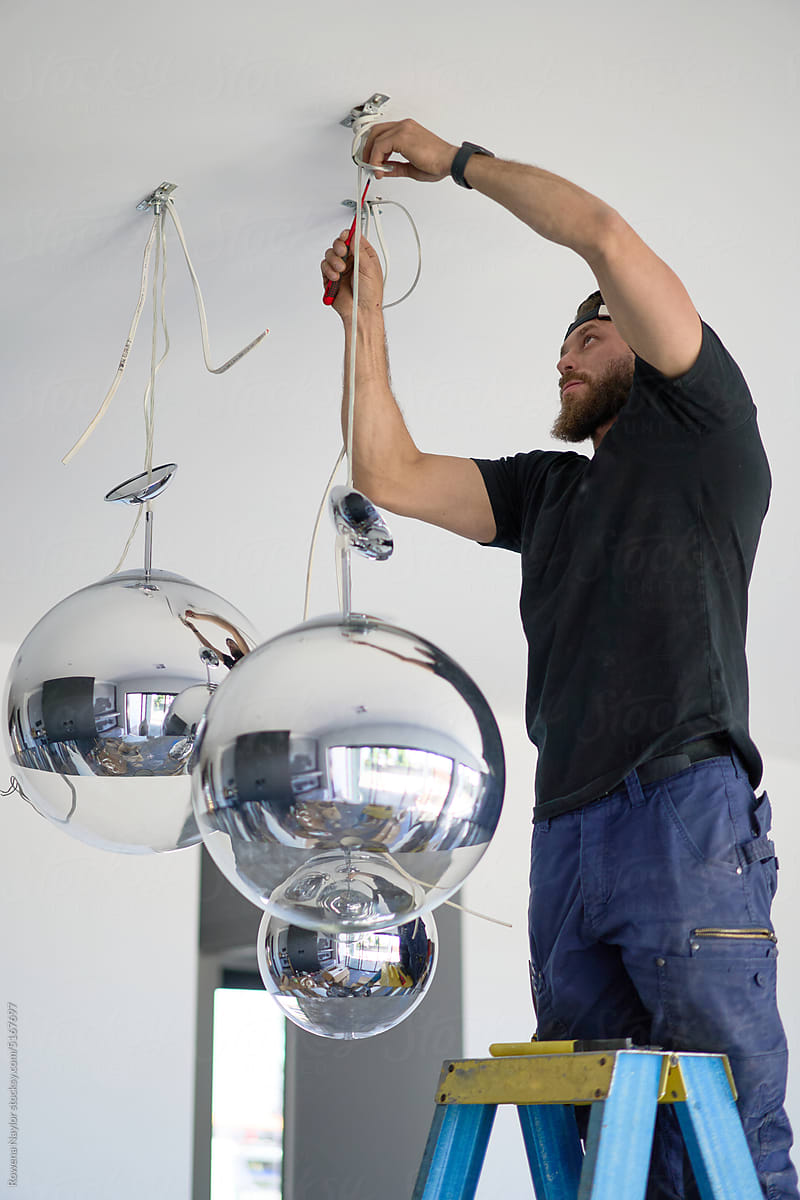 Electrician hanging globe lights