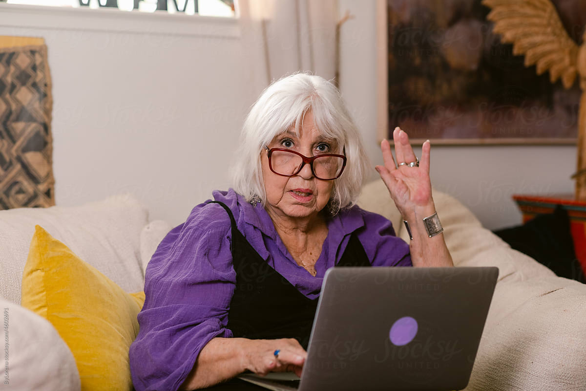 Elderly woman with laptop sitting at home