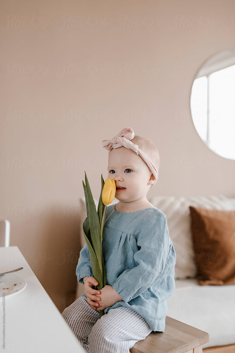 Pretty little girl with yellow tulip in hands.