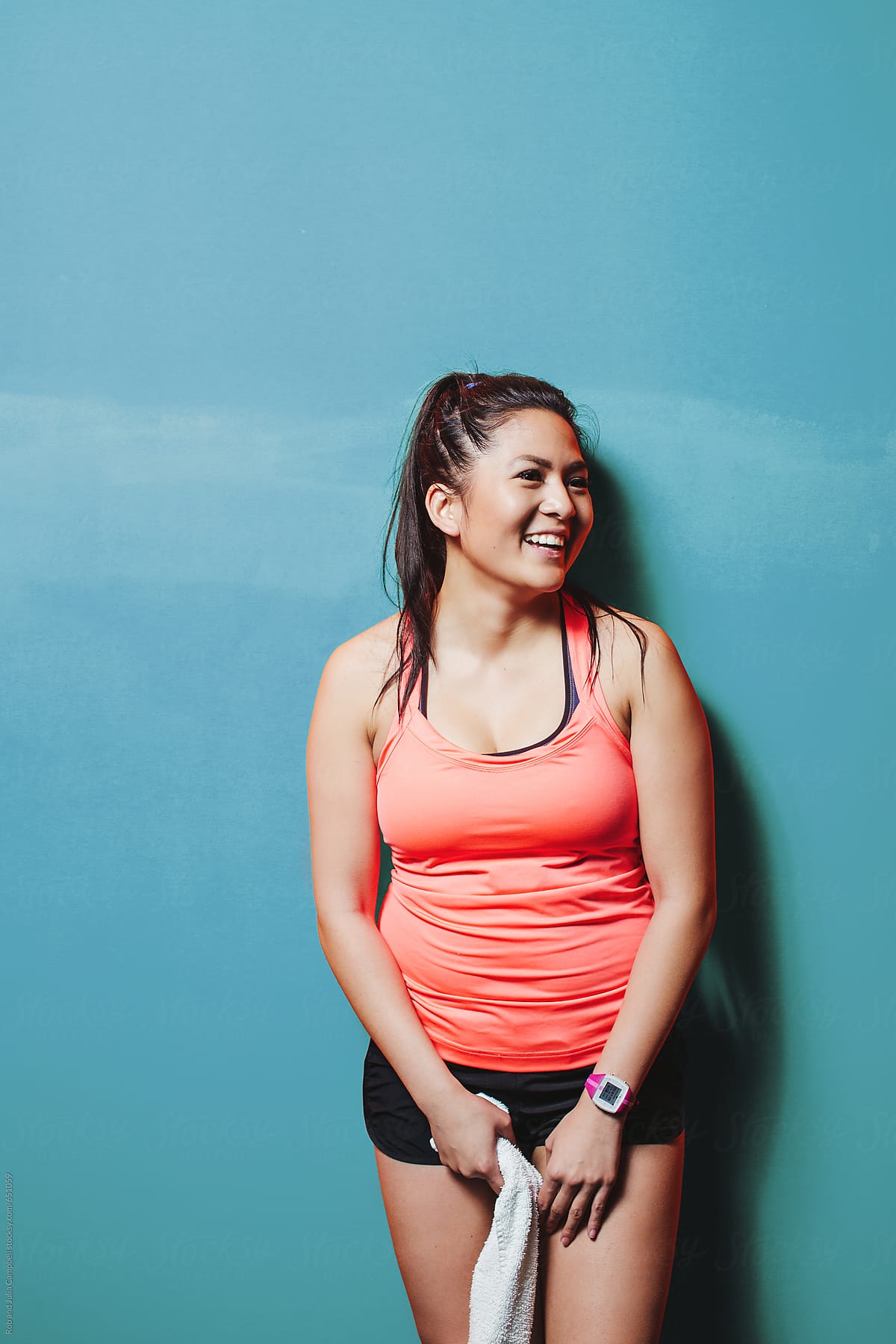 Happy asian woman smiling near blue wall - sweaty and smiling after hard workout
