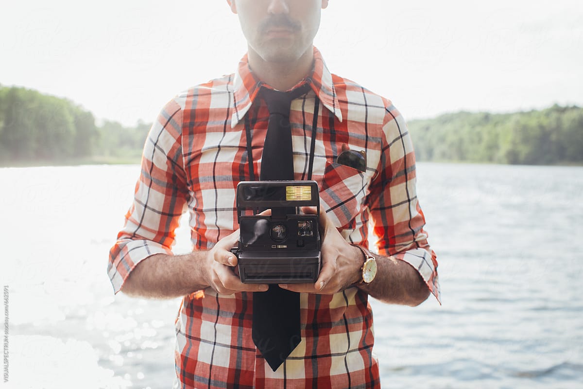 Retro-Styled Man Holding Instant Film Camera in Front of Chest