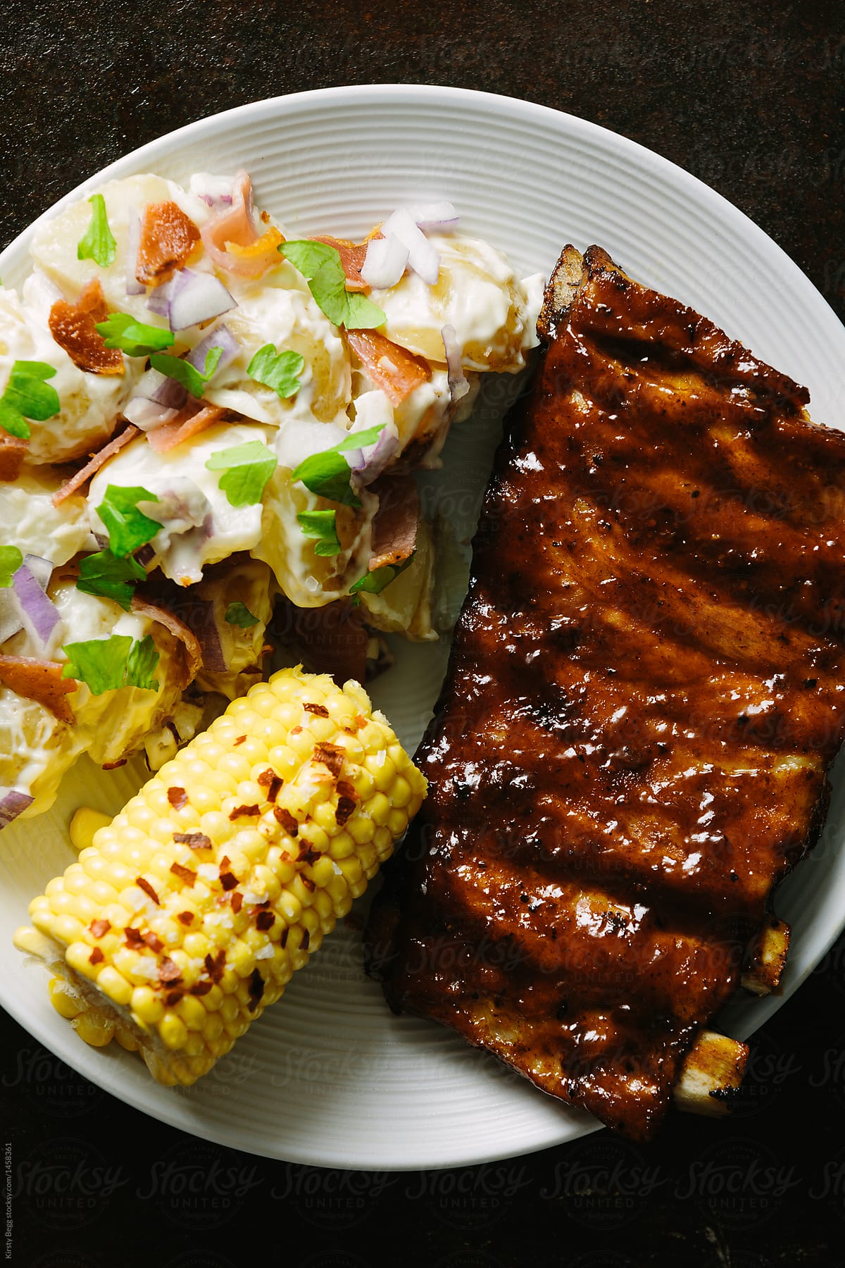 Plate of ribs, potato salad and corn on the cob