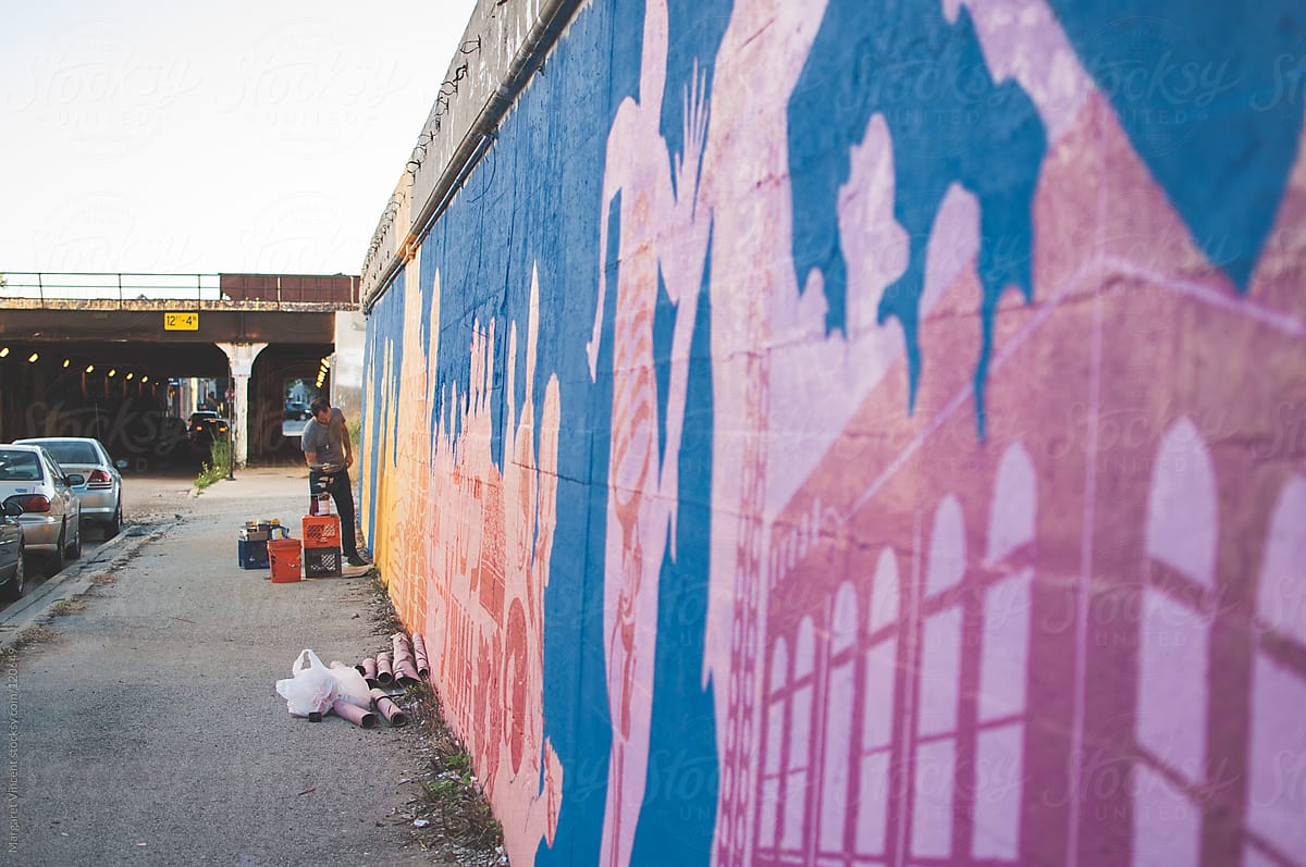 artist paints mural on a city street