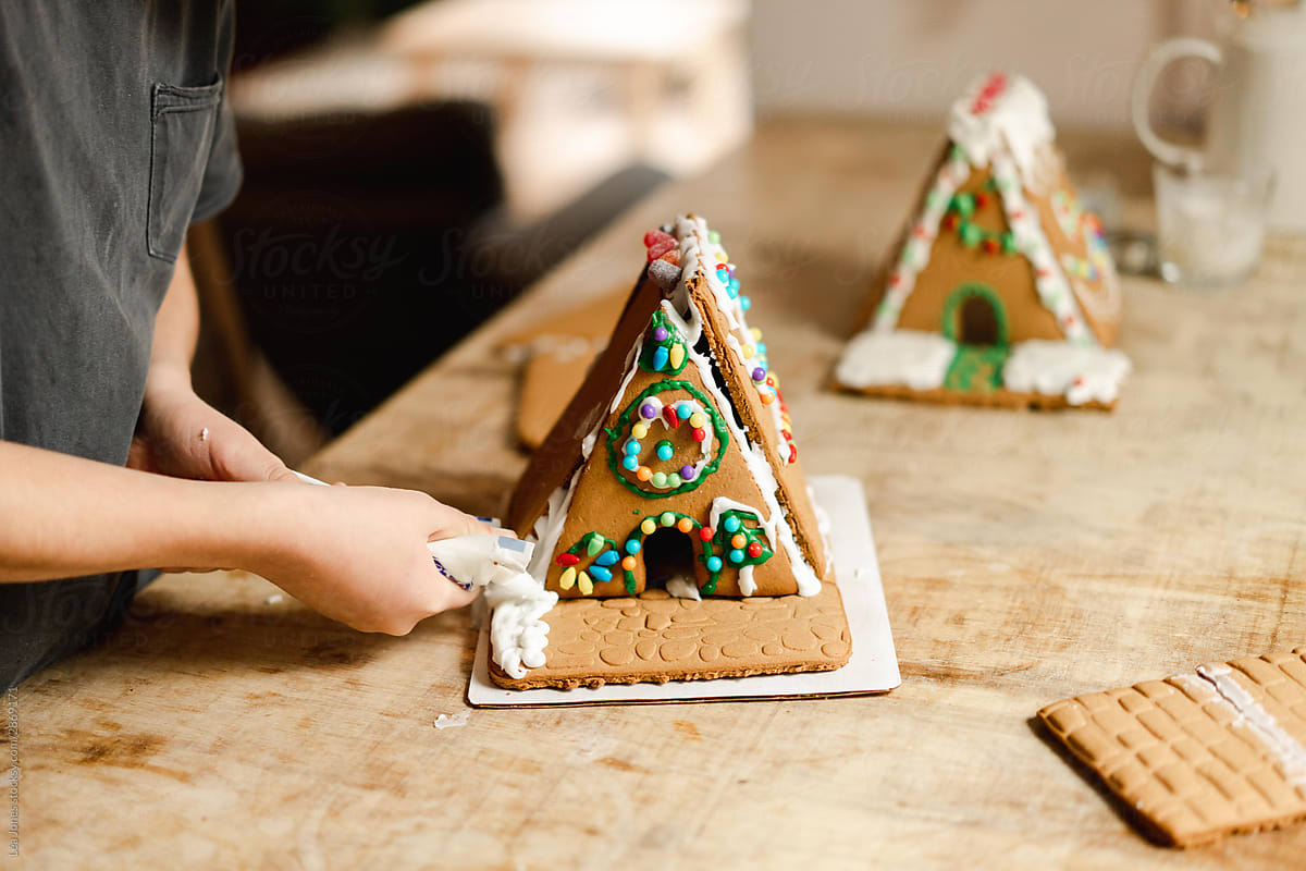 boy building and decorating a gingerbread house