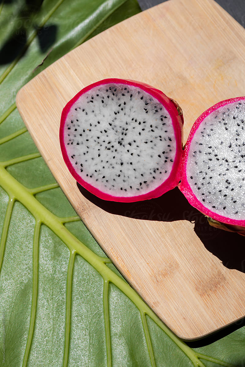A pink pitahaya on a wooden chopping board