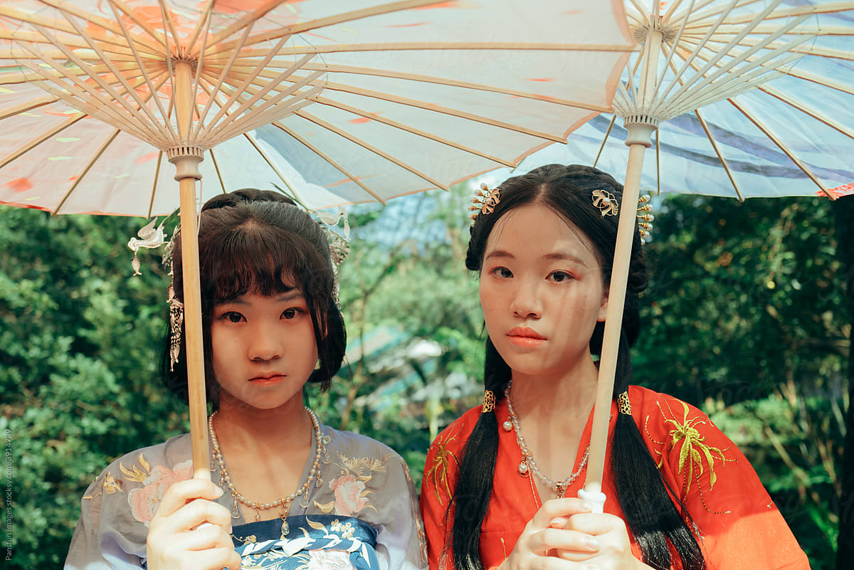 Two Asian teenage girls holding umbrellas