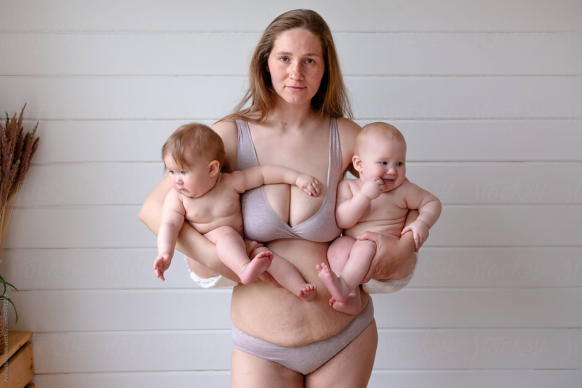 woman in lingerie posing holding two babies