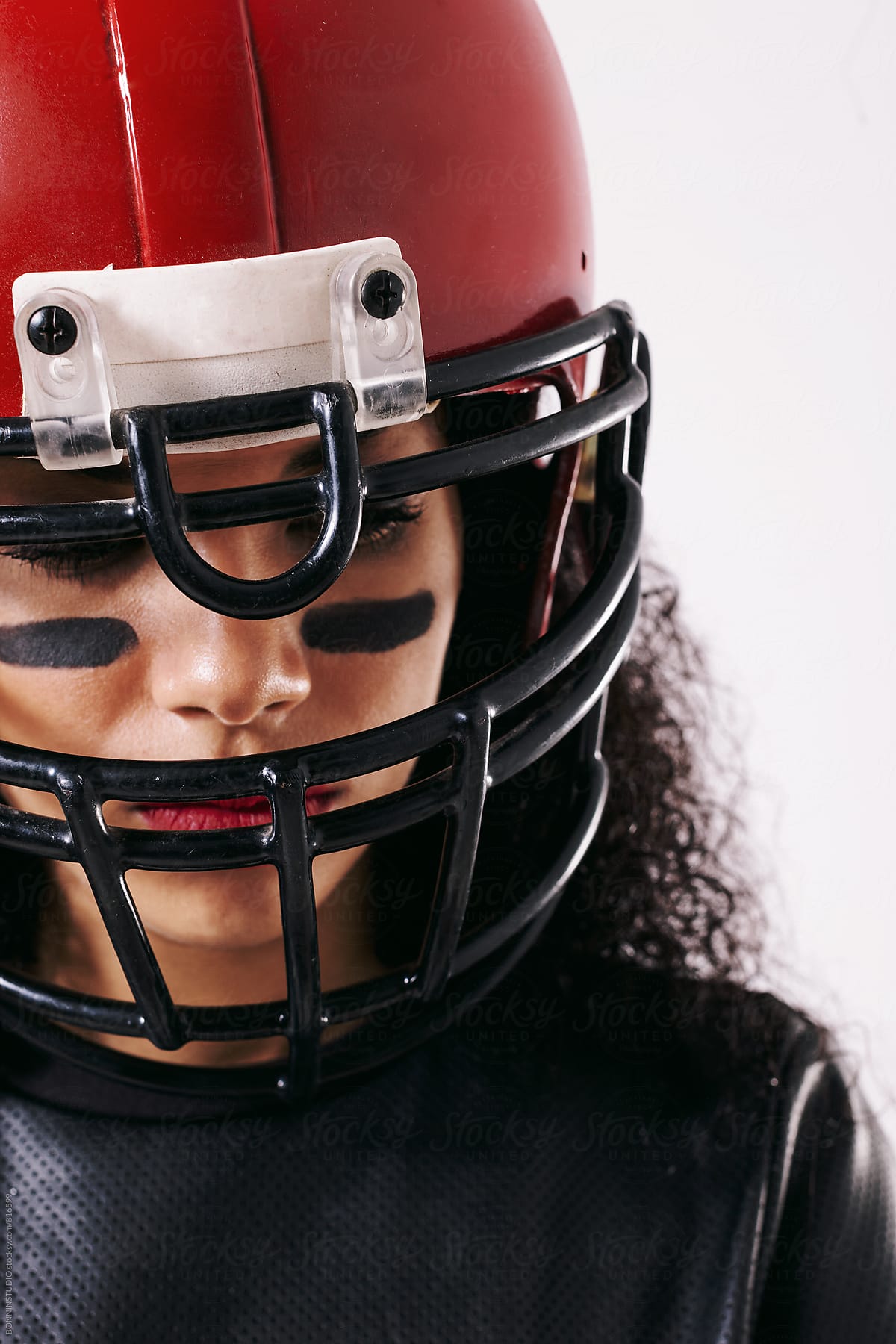 Closeup portrait of a woman wearing a red football helmet.