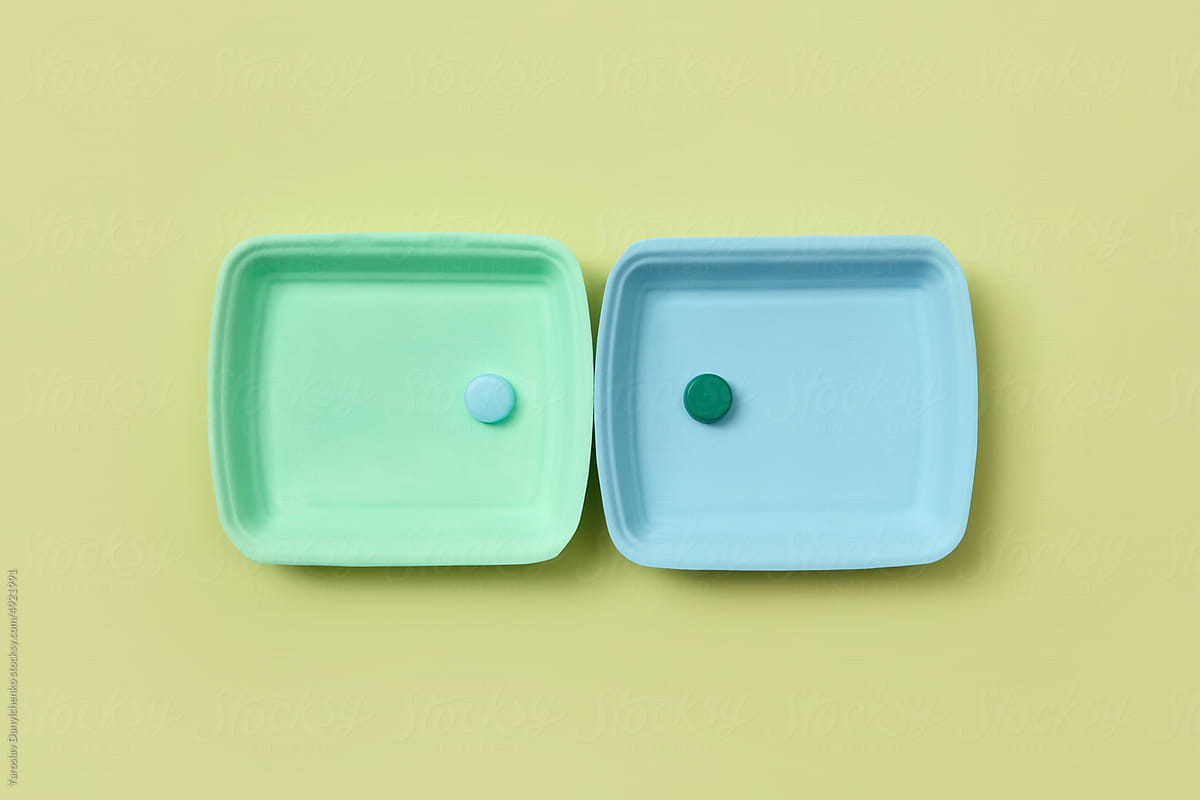 Two plastic plates and lids on green background.