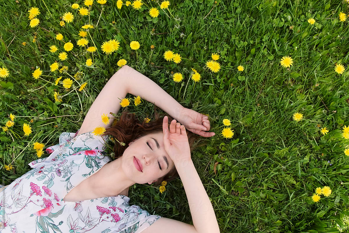 Woman Lying In The Grass Surrounded By Dandelions Del Colaborador De Stocksy Jamie Grill