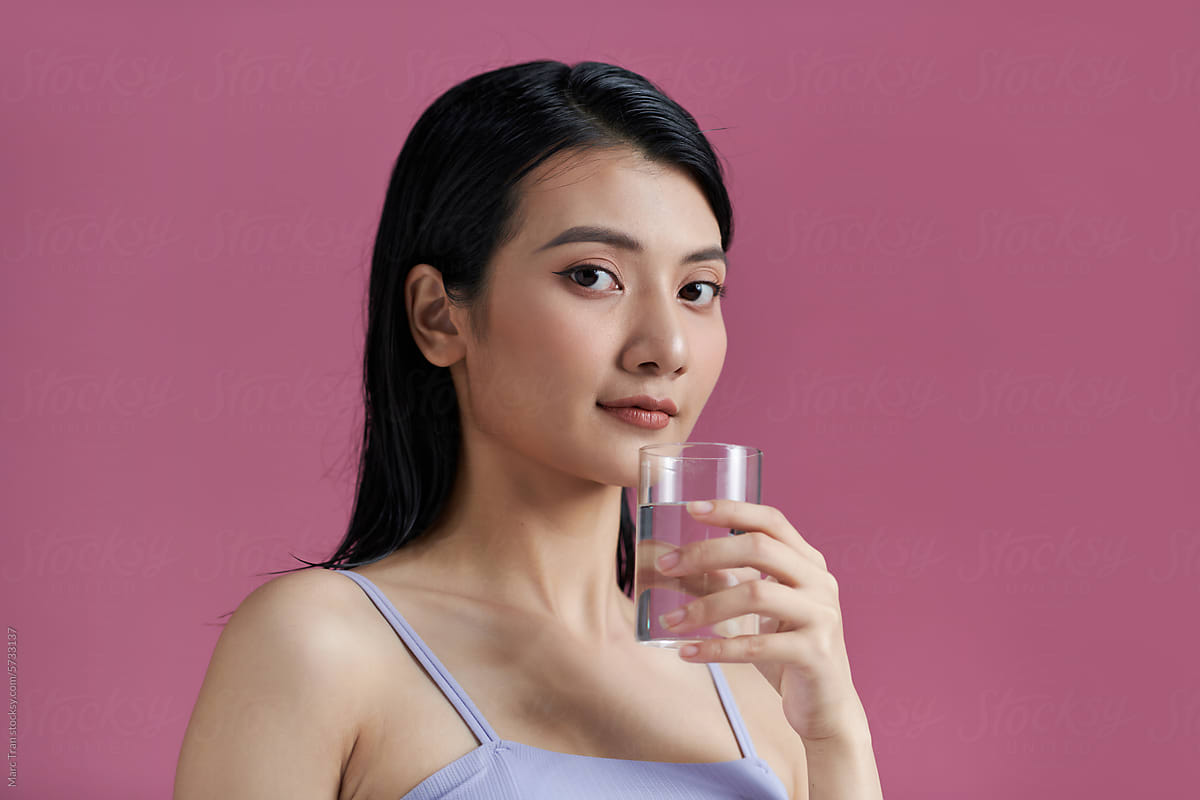Portrait of happy smiling young woman with glass of fresh water