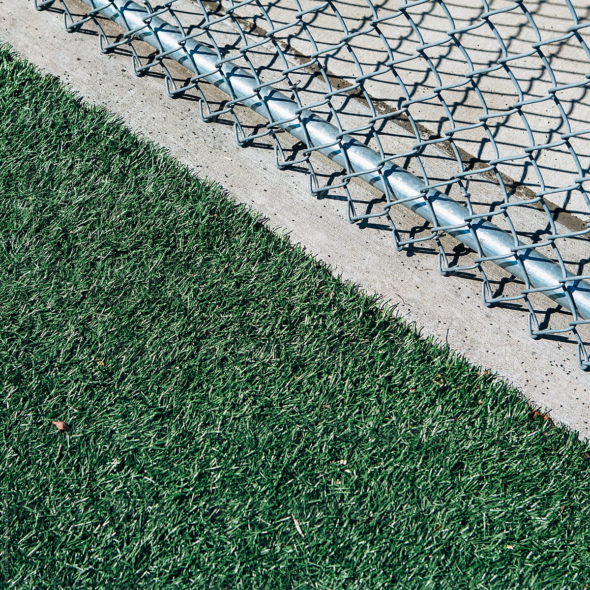 Chain link fence on edge of artificial turf sports field, close up