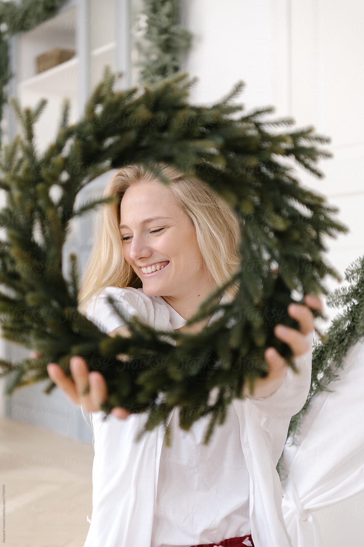 Cheerful blonde woman posing with wreath