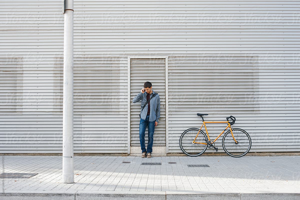 Young man on the street with urban bike  and talking with phone