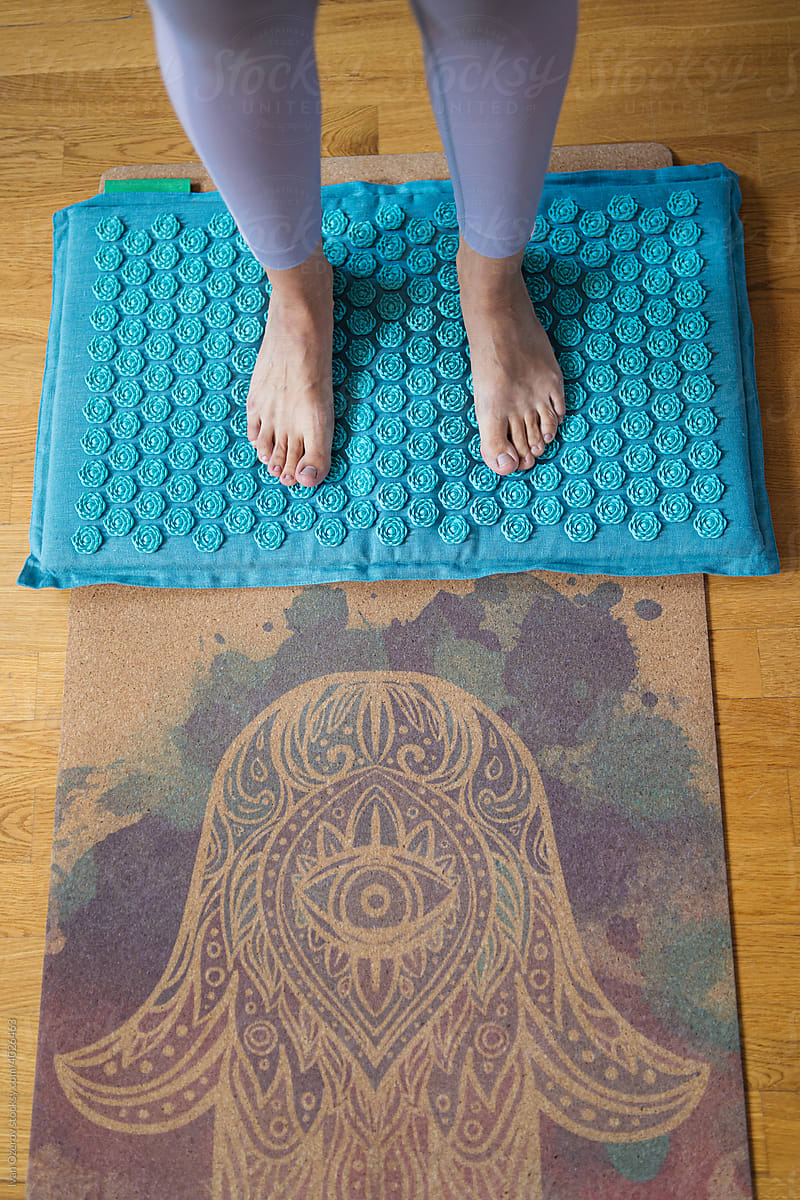anonymous woman stands on acupuncture yoga mat