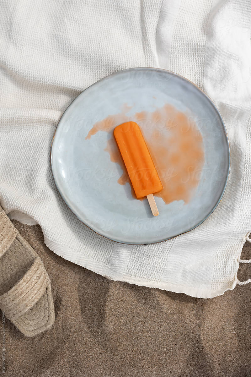 Melt popsicle on plate on beach
