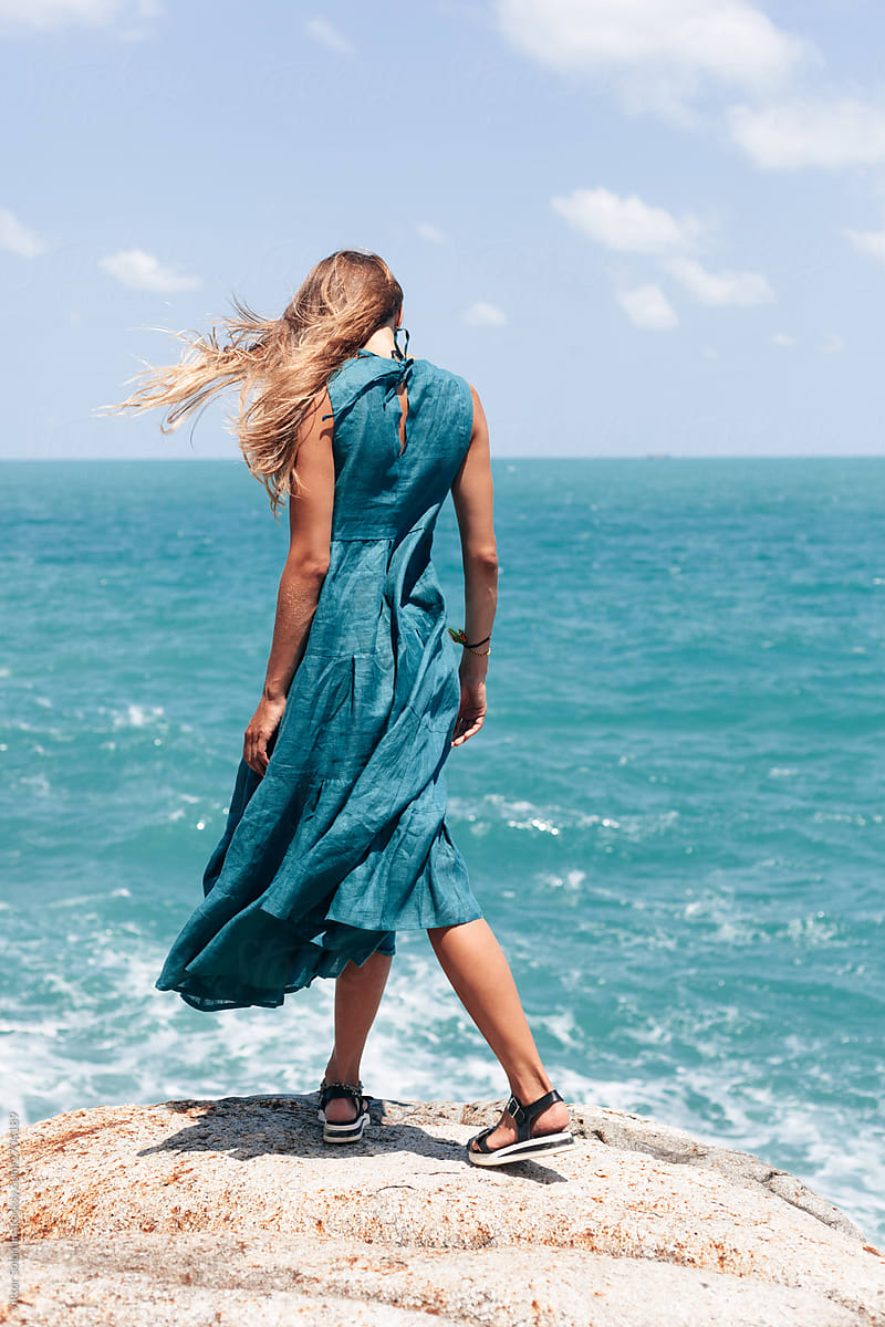 Blue sea and dress fashion woman standing alone on rock