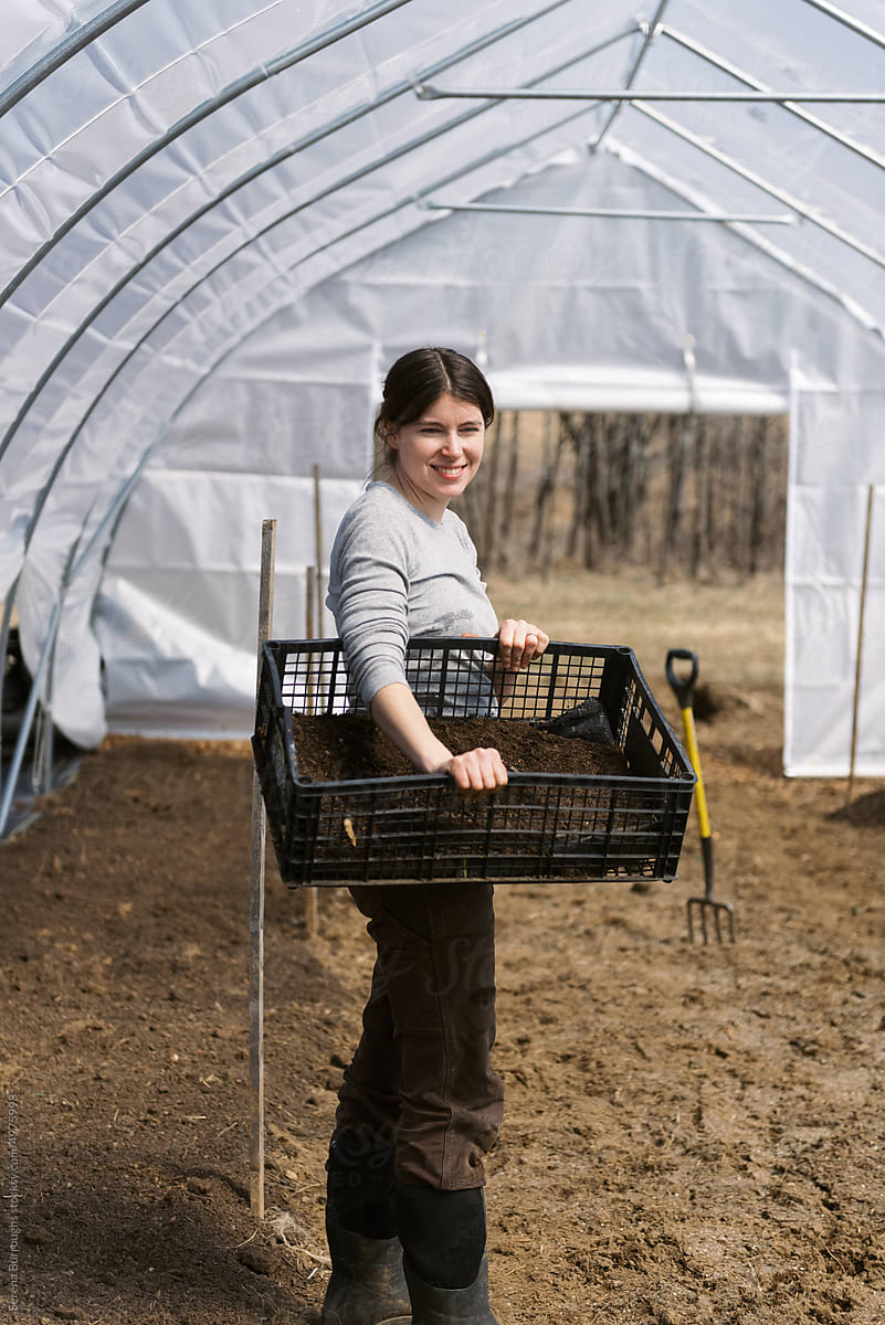 small business woman holding crate while in her hoop house