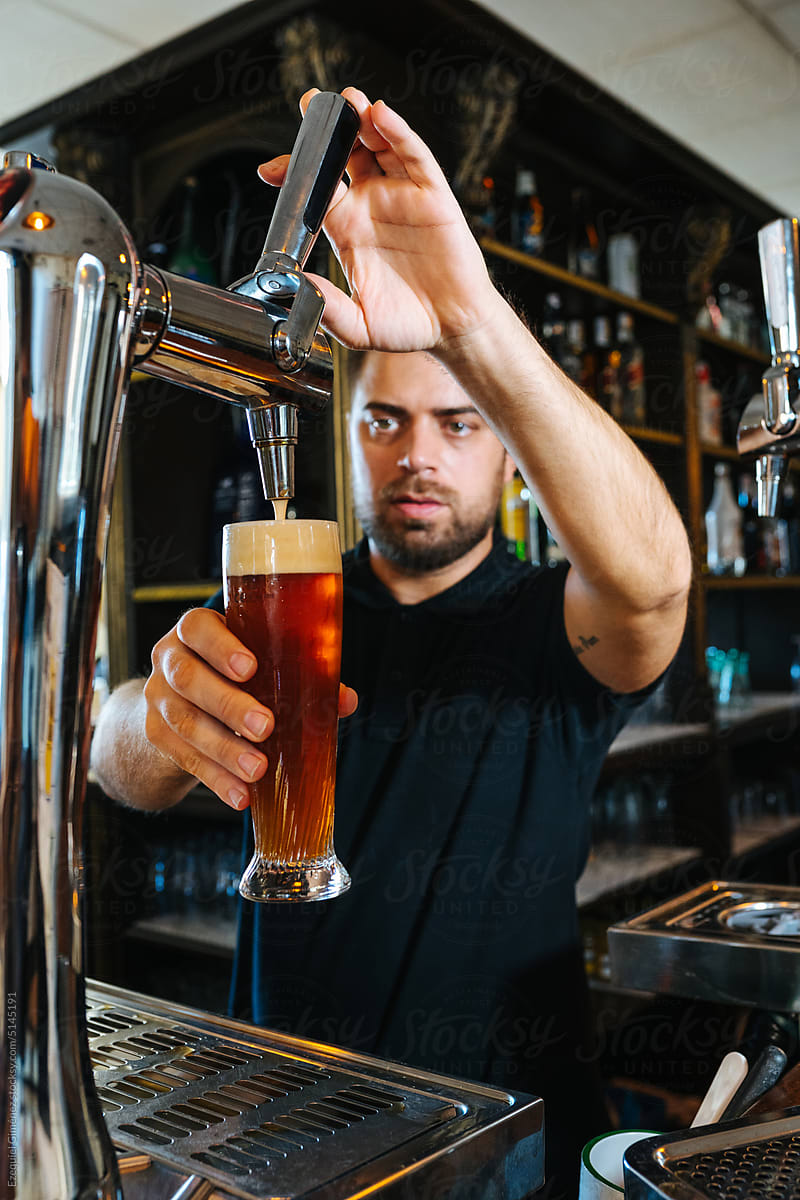 Bearded bartender pouring beer into glass