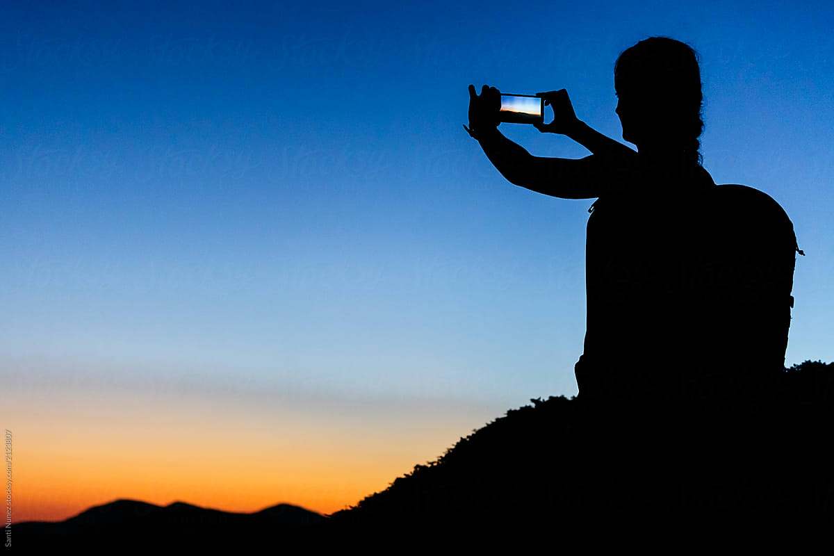 Silhouette of traveler taking photo of landscape