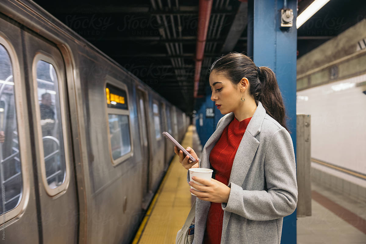 Woman using smartphone on the subway platform