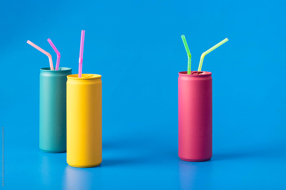 Yellow, turquoise and pink cans with colorful straws on blue background