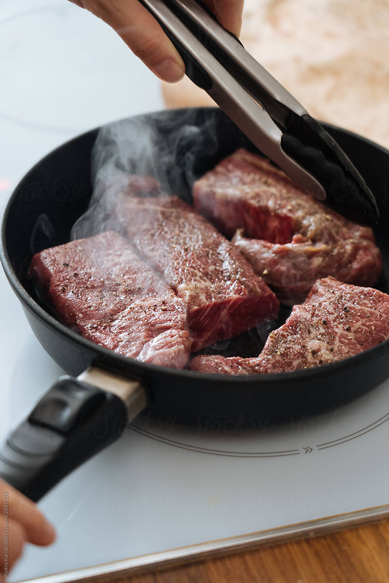 Frying delicious beef steaks on pan