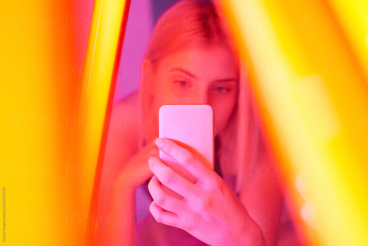 Woman in vivid neon lamp taking selfie