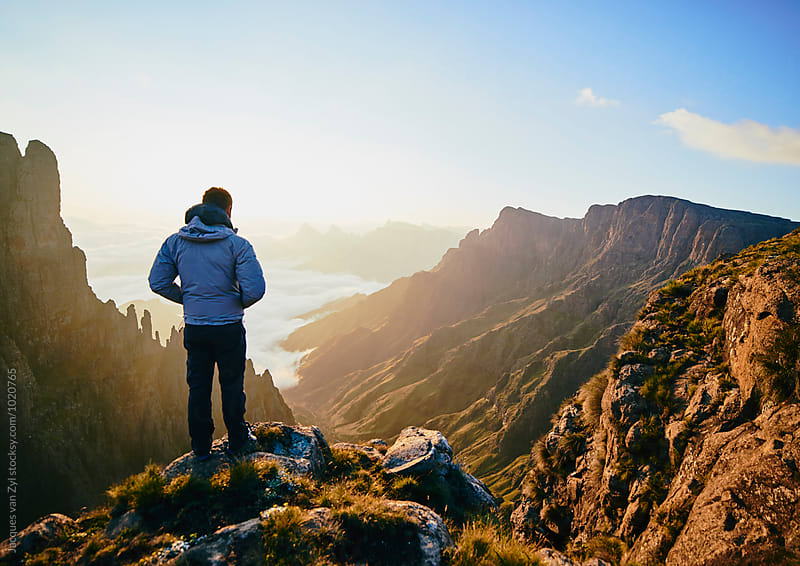 A Male hiker standing on a mountain edge admiring the spired mountain valley at sunrise.