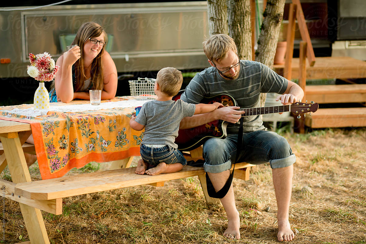 Young dad plays guitar with family at picnic table