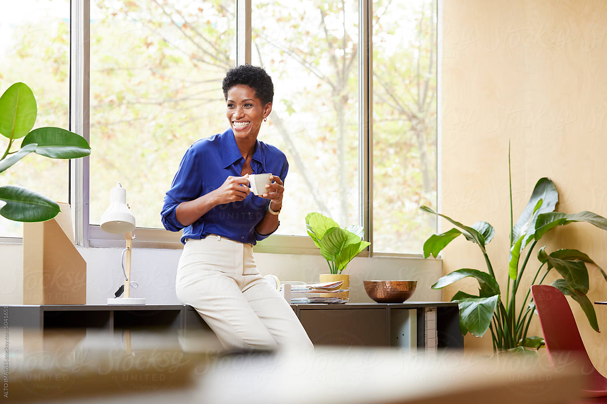 Smiling black businesswoman having coffee in office