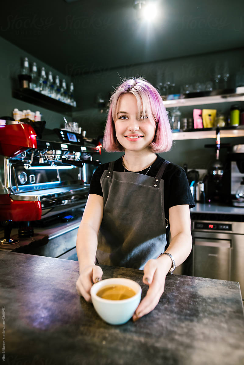 Smiling barista woman with cappuccino at coffee shop